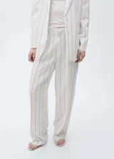 Pantalón de vestir de tiro medio, color blanco con rayas verticales negras, de corte wide leg y largo hasta el tobillo. Cierre frontal con botón, gancho y cremallera oculta. Con bolsillos laterales y trabillas para cinturón.
