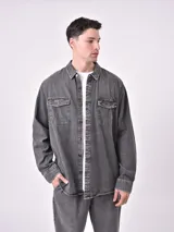 Sobrecamisa de denim gris con dos bolsillos frontales con solapa y cierre de botones.