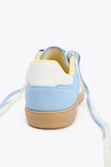 Zapatillas deportivas celestes con detalles en blanco y amarillo.