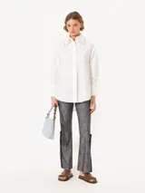 Camisa blanca de poplin con cuello clásico y mangas largas. Detalle de piedras engarzadas en el borde del cuello y botones de pasta al tono en el frente.