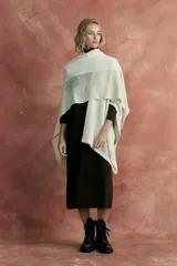 Ruana de tejido de punto color crudo, con diseño calado en la parte superior.