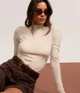 Short de sarga color blanco, corte mom, tiro alto, con trabillas en la cintura y bolsillos. Tiene cierre tradicional por botón y cremallera.