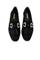 Mocasines negros de gamuza con detalle de borlas y aplique metálico dorado.