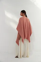 Ruana tejida color rosa claro con flecos en el borde.