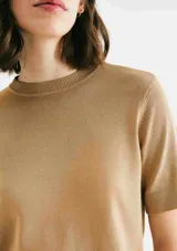 Blusa color beige de tejido de punto, con cuello redondo y mangas cortas.