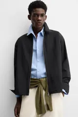 Sobrecamisa color crema de tejido técnico ligero, corte regular fit, cuello solapa, manga larga con puños abotonados, bajo ajustable con elástico en laterales y cierre frontal con cremallera.