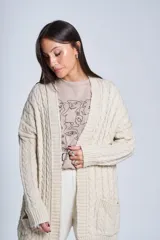 Saco tejido color crema con diseño de ochos y bolsillos frontales.