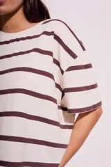 Remera de algodón color crudo con rayas horizontales marrones, corte oversize y mangas cortas.