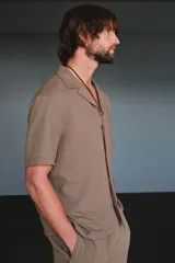 Camisa de manga corta color marrón claro, de punto texturizado de mezcla de algodón, con cuello abierto, tapeta lisa y bajo recto.