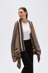 Poncho de tejido grueso con cierre frontal parcial. Presenta un diseño geométrico con bloques de color y patrones a cuadros en tonos marrón oscuro, mostaza, gris y beige.