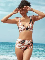 Top de bikini con estampado abstracto en tonos marrón, blanco y negro. Tiene corte triangular, breteles con lazos y copas removibles.