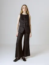 Chaleco negro con cierre frontal abotonado y bolsillos simulados.