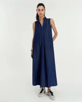 Vestido largo de denim azul, corte evasé, sin mangas, con cuello mao, falsa cartera en forma de escote en V, tabla en el centro delantero, bolsillos laterales, tablón encontrado en centro espalda y ruedo redondeado con tajos en laterales.