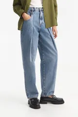Jean largo de denim azul claro, tiro medio, con corte amplio y pinzas delanteras. Presenta bolsillos delanteros y trabillas para cinturón.