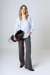 Blusa celeste con rayas verticales blancas, cuello mao y mangas largas abullonadas con puños elásticos.