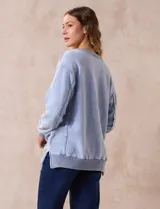 Buzo celeste de algodón con efecto lavado, escote en V, cuello, puños y ruedo acanalados y tajos laterales.