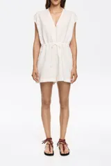 Mono corto de lino color blanco, con escote en pico, manga corta murciélago, corte ajustado en la cintura con lazos y maxilágrima en la espalda.