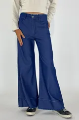 Pantalón de mezclilla azul con corte amplio y detalles deshilachados en el dobladillo.