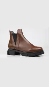Botas Chelsea de cuero color marrón con elástico negro en los laterales y suela track negra.