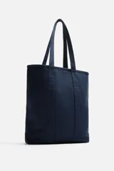 Bolso tipo shopper color azul marino, fabricado en tejido de algodón. Tiene doble asa de mano y un bolsillo plano en el interior.