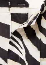 Pantalón de mujer con estampado de cebra en tonos blanco, negro y dorado. Diseño wide leg, tiro medio y detalle de pinzas. Cierre delantero con botón, gancho y cremallera ocultos.