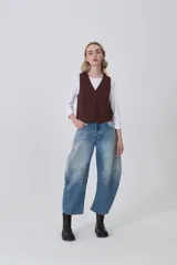 Chaleco negro de poliéster con escote en V y cierre frontal de botones. Diseño holgado.