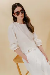 Blusa blanca de lino con mangas balloon y detalle de tablón en el hombro. Tiene mangas largas con detalle de 2 pespuntes elásticos en contratono.