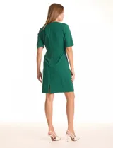 Vestido midi verde de crepe, con cuello a la base, escote entrelazado y mangas cortas. Cierre invisible en la espalda y tajo en el ruedo.