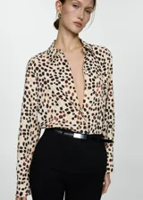 Camisa de manga larga con estampado de cebra en blanco y negro, cuello camisero y cierre frontal con botones.
