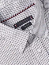 Camisa de vestir Tommy Hilfiger de corte clásico, confeccionada en tejido Oxford de algodón regenerativo con estampado a cuadros Tattersall en tonos blanco, azul y gris. Tiene cuello abotonado, cierre con botones, manga larga y logo bordado en el pecho.