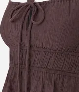 Blusa blanca con breteles anchos y escote cuadrado, detalle de lazo ajustable en el centro del busto y volado en el ruedo. El tejido es texturizado y ligero.