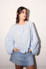 Camisa celeste super holgada con hombro caído y manga ancha. Tiene un volado en el cuello y efecto arrugado en la espalda.