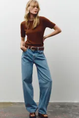 Jersey de punto negro, cuello redondo y manga corta, con acabados en rib en cuello, puños y ruedo.