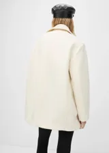 Abrigo blanco de lana virgen con diseño oversize, cuello de solapa y cierre de doble botonadura.