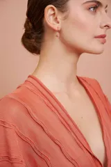 Arito dorado con dije de piedra rosa ovalada.