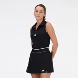 Musculosa deportiva negra con cuello polo y cierre parcial con cremallera. Logo de New Balance estampado en blanco en el pecho y falda negra tableada con short incorporado.