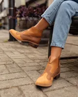 Botines de cuero marrón y blanco con diseño western, puntera redondeada y cierre lateral con cremallera. El talón tiene una tira de cuero para facilitar el calce.