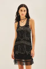 Vestido corto negro de tul bordado con piedras, lentejuelas, canutillos y flecos de mostacillas. Tiene escote redondo, calce recto y viso a tono con breteles finitos.