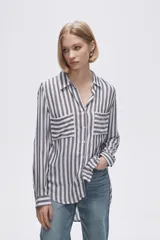 Camisa a rayas verticales grises y blancas, con cuello camisero, cierre frontal con botones, mangas largas con trabillas para enrollar y dos bolsillos de parche en el pecho.