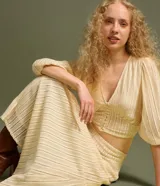 Blusa corta de encaje guipir de algodón con escote en V, botones frontales y manga larga abullonada con puño elástico.