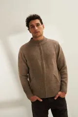 Campera de lana color crema, tejida con cierre delantero, cuello alto y bolsillos delanteros.