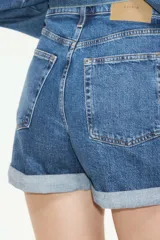 Short de jean de cinco bolsillos en denim de algodón levemente elástico. Modelo de tiro superalto con cierre, botón y dobladillo cosido.