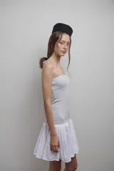 Vestido strapless confeccionado en tejido de punto gris, con falda plisada de popelina blanca.