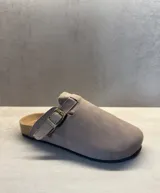Sueco de gamuza color beige con punta redondeada y cerrada, correa ajustable con hebilla metálica en el empeine y base de corcho con suela de goma.