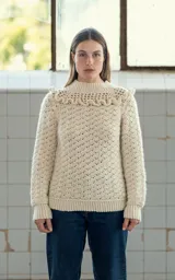 Sweater color crema tejido a crochet con lana merino, cuello alto con volados y mangas largas.