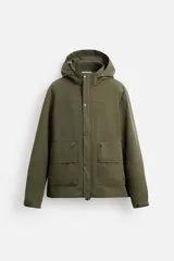 Parka verde militar confeccionada en tejido técnico ligero resistente al viento, con cuello alto, capucha, manga larga con puños ajustables, bolsillos de plastrón con solapa en la cadera, bolsillo interior, bajo ajustable con elásticos y cierre frontal con cremallera oculta por solapa con botones a presión.