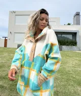 Buzo largo con cuello alto de polar color crema y cuerpo con estampado de cuadros en tonos celeste, amarillo y blanco.