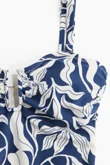 Traje de baño enterizo con estampado floral en azul y blanco, con breteles ajustables extraíbles, alambre en forma de U en la parte central del busto, copas con relleno extraíble, piernas de corte alto y cobertura media en la parte de atrás.