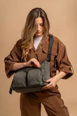 Bandolera de tafeta impermeable, liviana, con dos compartimientos principales, dos bolsillos con cierre y correa regulable con hebilla.