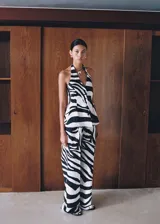 Pantalón de mujer con estampado de cebra en tonos blanco, negro y dorado. Diseño wide leg, tiro medio y detalle de pinzas. Cierre delantero con botón, gancho y cremallera ocultos.